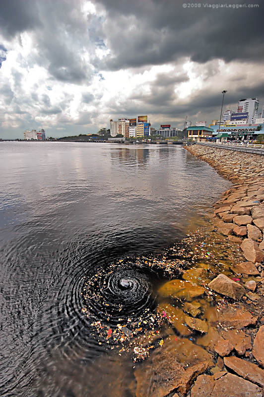 Johor Bahru sullo sfondo, vortice nell'acqua e spazzatura in primo piano