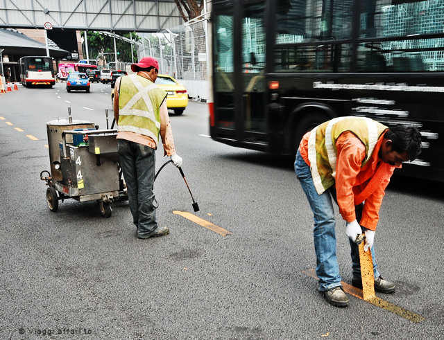 Operai rimuovono strisce gialle dalle strade di Singapore